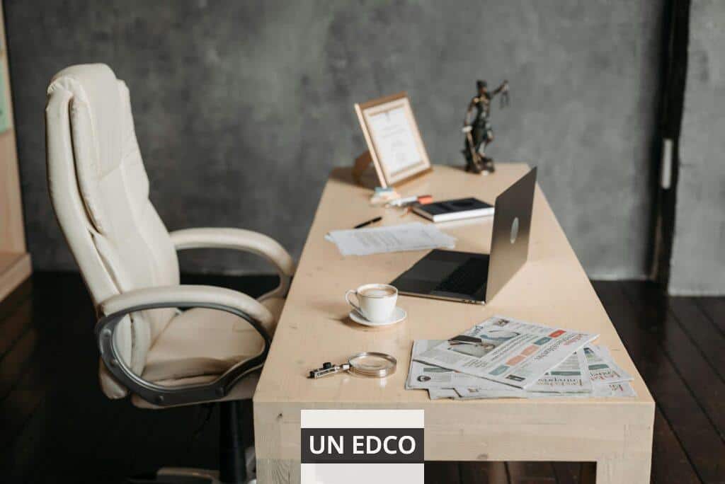 A clean office workspace featuring a cup of coffee, laptop, and newspapers on a wooden desk for a productive environment.